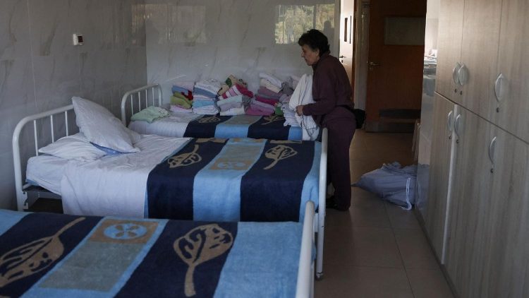 A patient stands near beds inside a room at De La Croix Psychiatric Hospital in Jal el-Dib