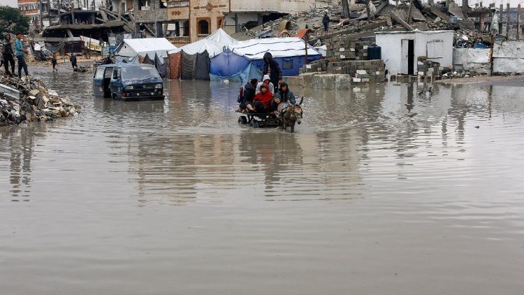Displaced Palestinians ride a donkey-drawn cart on a rain-flooded street in Gaza City