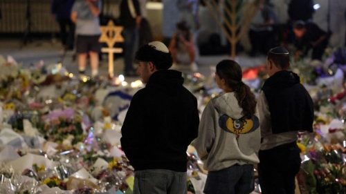 Persone in raccoglimento davanti ai fiori per le vittime dell'attentato di Bondi beach
