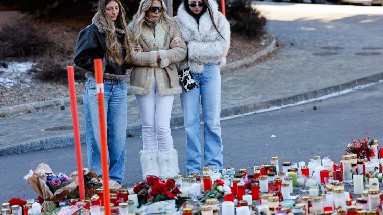 1 जनवरी की रात को लगी आग से मरे लोगों को मोमबत्ती चढ़ाते लोग 