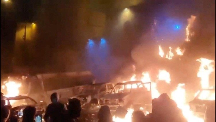 Protestors gather around burning vehicles in Tehran