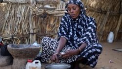 A displaced Sudanese mother of four, prepares food at a camp shelter amid the ongoing conflict