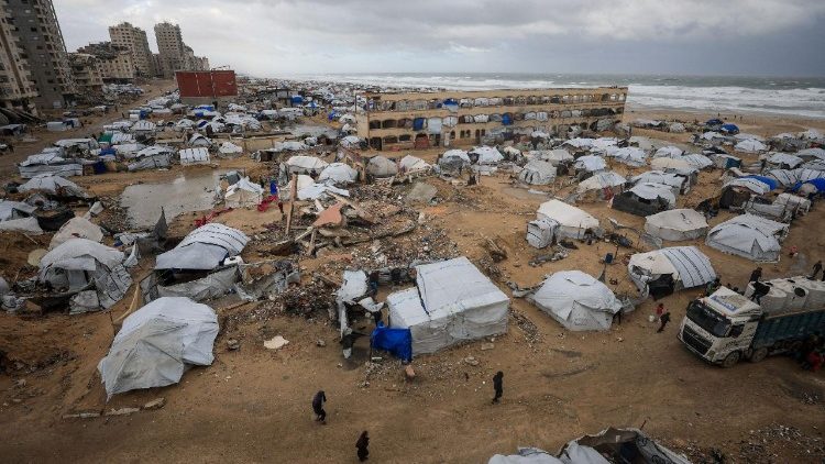 Palestinos caminham ao lado de tendas usadas por pessoas deslocadas, em um dia ventoso de inverno, na Cidade de Gaza, 13 de janeiro de 2026. REUTERS/Dawoud Abu Alkas City 