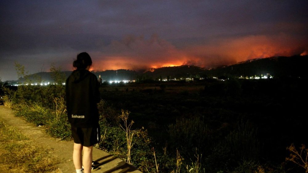 Pessoas observam a fumaça e as chamas subindo enquanto um incêndio florestal queima em Concepción, Chile, após um incêndio na região de Biobío, onde, segundo a mídia local, múltiplos focos de incêndio provocaram evacuações de emergência, 18 de janeiro de 2026. REUTERS/Juan Gonzalez