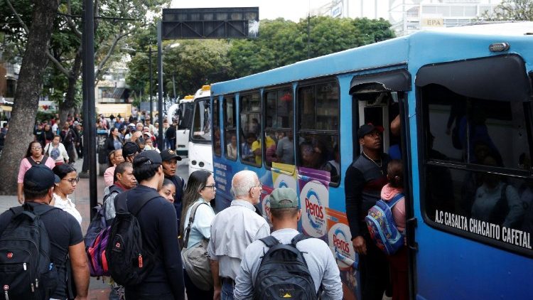 Des gens attendent à un arrêt de bus, à Caracas.