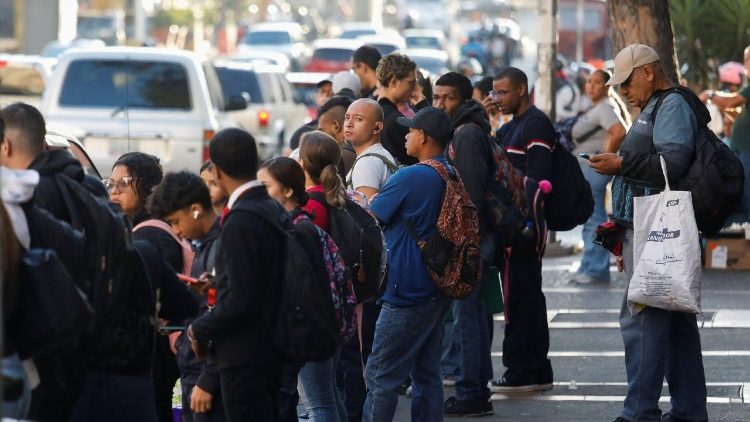 People wait at a bus stop in Venezuelan capital Caracas