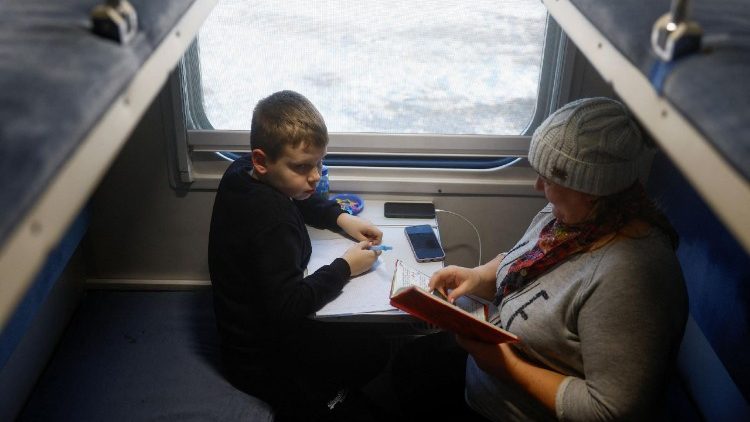 Oleksii, de 9 anos, faz sua tarefa escolar com a ajuda de sua m&atilde;e, Iryna, de 42 anos, dentro de um vag&atilde;o de trem transformado em um ponto de ajuda humanit&aacute;ria, tamb&eacute;m chamado de "Ponto da Invencibilidade", onde as pessoas podem carregar seus dispositivos, fazer refei&ccedil;&otilde;es quentes e tomar bebidas durante um apag&atilde;o ap&oacute;s infraestruturas civis cr&iacute;ticas terem sido atingidas por recentes ataques de m&iacute;sseis e drones russos, em meio ao ataque da R&uacute;ssia &agrave; Ucr&acirc;nia, na cidade de Brovary, na regi&atilde;o de Kyiv, Ucr&acirc;nia, em 21 de janeiro de 2026. REUTERS/Valentyn Ogirenko