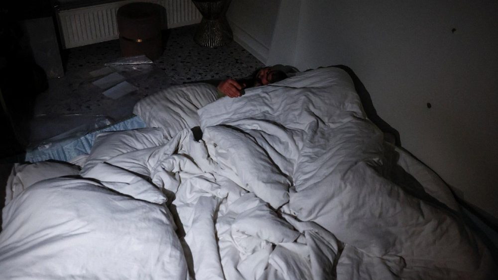 Denys Davydenko, de 40 anos, e seus filhos Maksym, de 11, Tymofiy, de 6, e Stephanie, de 2, dormem em uma cama improvisada no chão do café onde estão hospedados porque seu apartamento não tem aquecimento nem água quente e sofre frequentes cortes de energia devido aos ataques da Rússia à Ucrânia, em Kiev, Ucrânia, 1º de fevereiro de 2026.REUTERS/Alina Smutko.