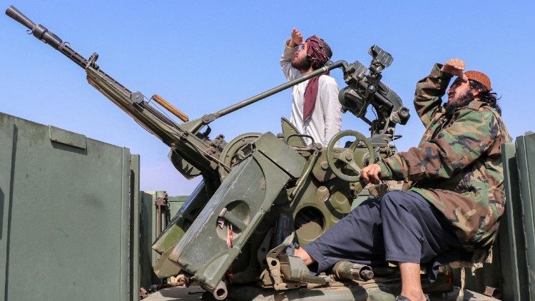 Taliban soldiers sit next to an anti-aircraft gun while on lookout for Pakistan's fighter jets, in Khost province