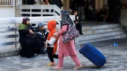 Mulher deslocada com uma criança caminha do lado de fora de uma escola transformada em abrigo, após a escalada entre o Hezbollah e Israel em meio ao conflito entre os EUA e Israel com o Irã, em Beirute, Líbano.
