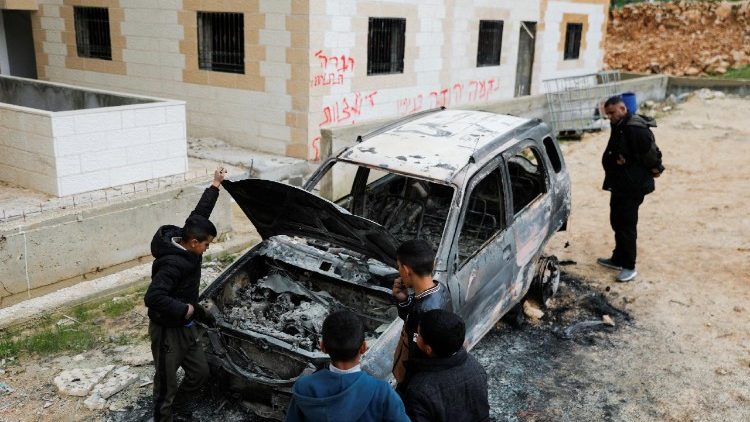 People check a damaged car, which Palestinians say was burned by Israeli settlers, near Hebron