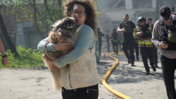 Uma moradora com um cachorro e socorristas correm durante um alarme de ataque a&eacute;reo no local do jardim de inf&acirc;ncia atingido por um ataque de drone russo, em meio ao ataque da R&uacute;ssia &agrave; Ucr&acirc;nia, em Sumy, Ucr&acirc;nia, em 6 de maio de 2026. REUTERS/Stringer