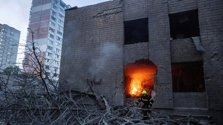 Um bombeiro est&aacute; em frente a um pr&eacute;dio em chamas ao lado de um edif&iacute;cio de apartamentos que foi danificado e parcialmente desabado durante ataques com m&iacute;sseis e drones russos, em meio ao ataque da R&uacute;ssia &agrave; Ucr&acirc;nia, em Kiev, Ucr&acirc;nia, em 14 de maio de 2026. REUTERS/Thomas Peter