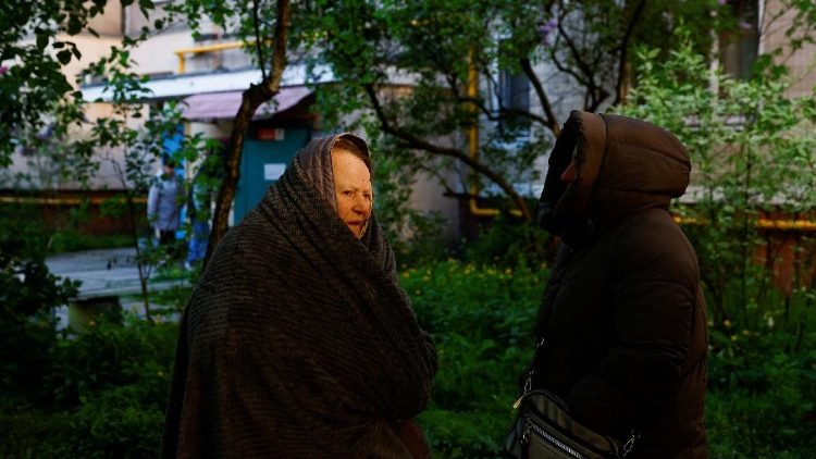 Moradores pr&oacute;ximos a um pr&eacute;dio parcialmente desabado, danificado durante ataques com m&iacute;sseis e drones russos, em meio ao ataque da R&uacute;ssia &agrave; Ucr&acirc;nia, em Kiev, Ucr&acirc;nia, 14 de maio de 2026. REUTERS/Valentyn Ogirenko