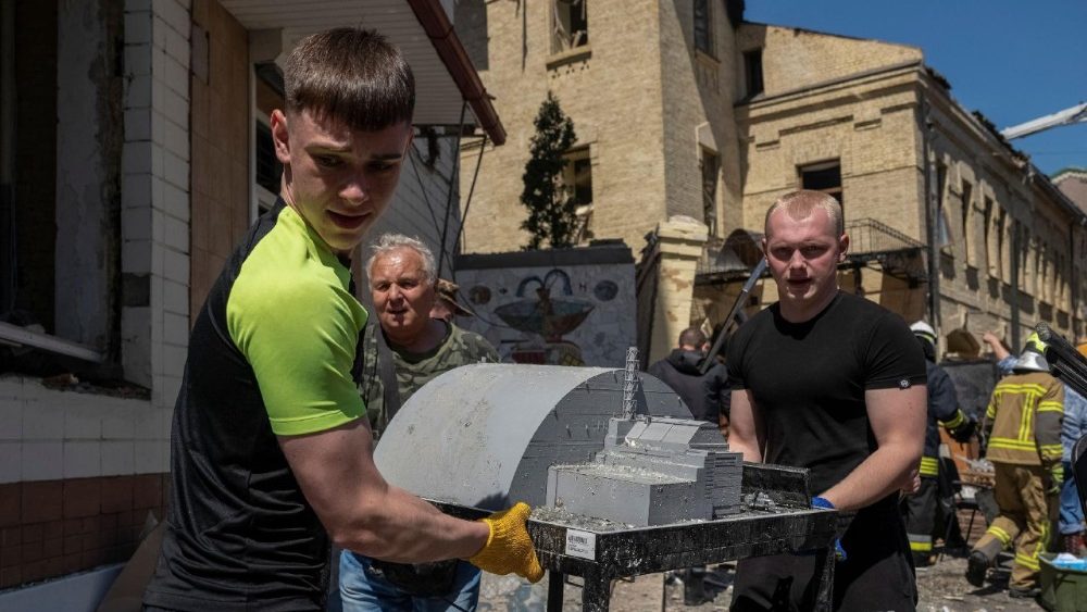 Operários carregam a maquete de uma nova estrutura de confinamento seguro (NSC, na sigla em inglês) que cobre o antigo sarcófago, o qual abriga os restos do quarto reator danificado da usina nuclear de Chernobyl, do Museu Nacional de Chernobyl, danificado durante um ataque russo com mísseis e drones, em meio ao ataque da Rússia à Ucrânia, em Kiev, Ucrânia, 24 de maio de 2026. REUTERS/Viacheslav Ratynskyi