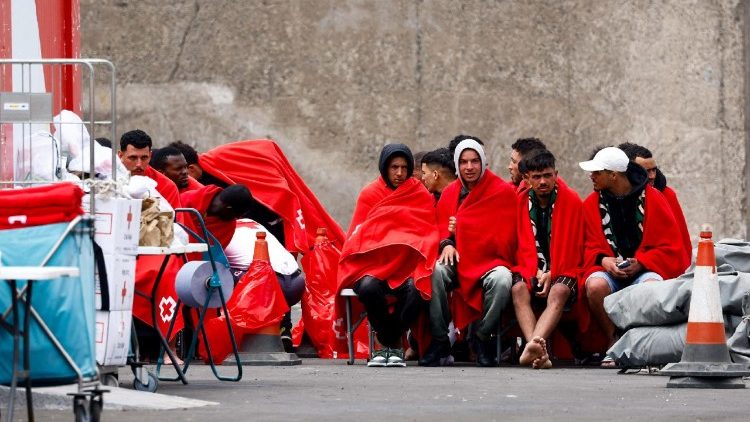 Migranti in attesa di assistenza dalla Croce Rossa dopo essere sbarcati da una nave della guardia costiera spagnola nel porto di Arguineguin