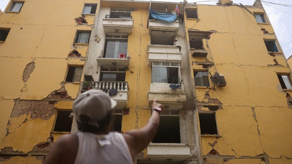 Maru Nunez, 59, aponta para um prédio residencial danificado em Mision Vivienda, que foi afetado pelos terremotos de 24 de junho, em Catia La Mar, estado de La Guaira, Venezuela, 12 de julho de 2026. REUTERS/Leonardo Fernandez Viloria