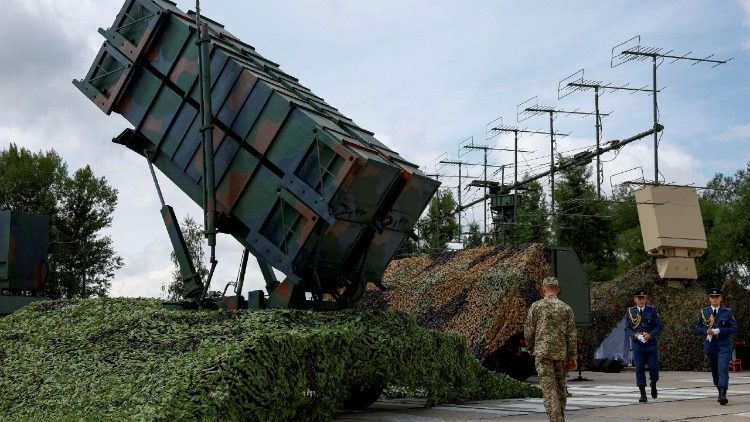 Militari ucraini camminano accanto a un lanciatore di un sistema di difesa aerea Patriot