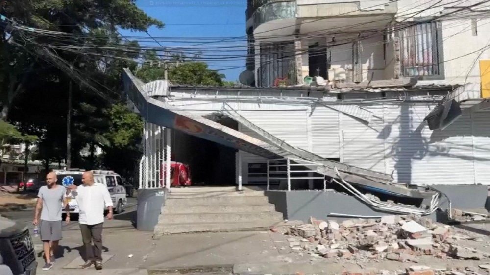 Pessoas caminham ao lado de um prédio danificado após um terremoto em Cali, Colômbia, em 10 de agosto de 2026, nesta captura de tela de um vídeo. REUTERS/Reuters TV