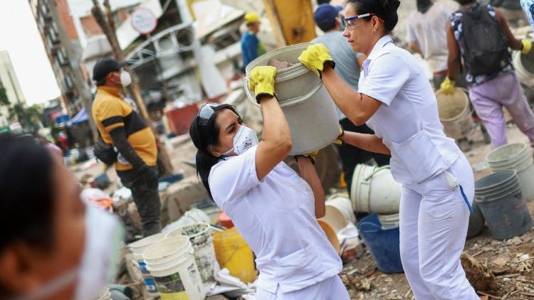 As enfermeiras Lizeth Diaz, de 35 anos, e Anyie Velazco, de 32, que trabalham no hospital em frente ao pr&eacute;dio que desabou, ajudam a remover os escombros ap&oacute;s se voluntariarem para ajudar depois de um turno de 9 horas, em meio a partes de uma estrutura destru&iacute;da ap&oacute;s um terremoto, em Cali, Col&ocirc;mbia, em 12 de agosto de 2026. REUTERS/Raquel Cunha
