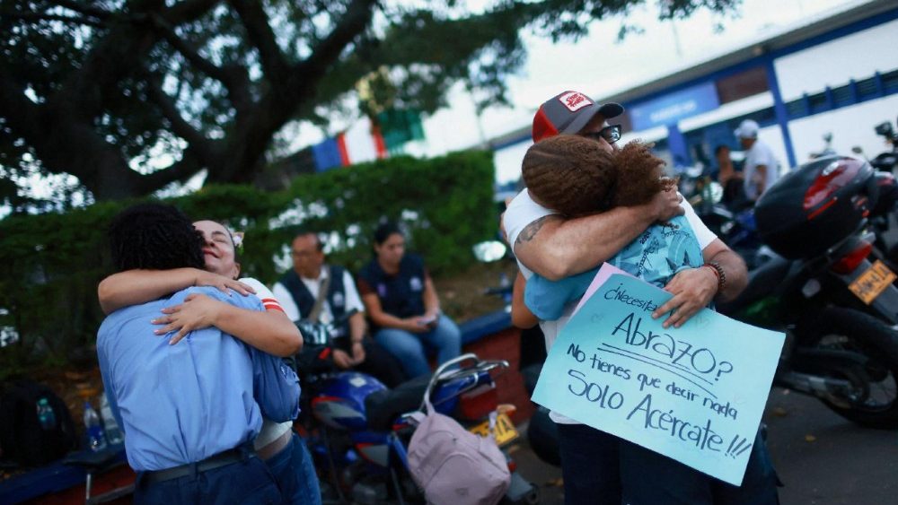 Rafael Gutierrez, 39, agricultor, e Yazmin Ceron, 54, professora, abraçam pessoas após um terremoto, na Unidad Deportiva Jaime Aparicio, em Cali, Colômbia, em 12 de agosto de 2026. REUTERS/Raquel Cunha