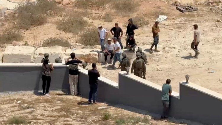 Abitanti di Qusra minacciati da coloni in un'immagine del 15 agosto (Reuters)