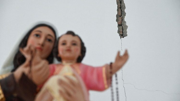 Una statua di Ges&ugrave; Bambino e Maria si erge di fronte a un muro crepato all'interno della Cattedrale di San Buenaventura, a seguito del terremoto del 10 agosto