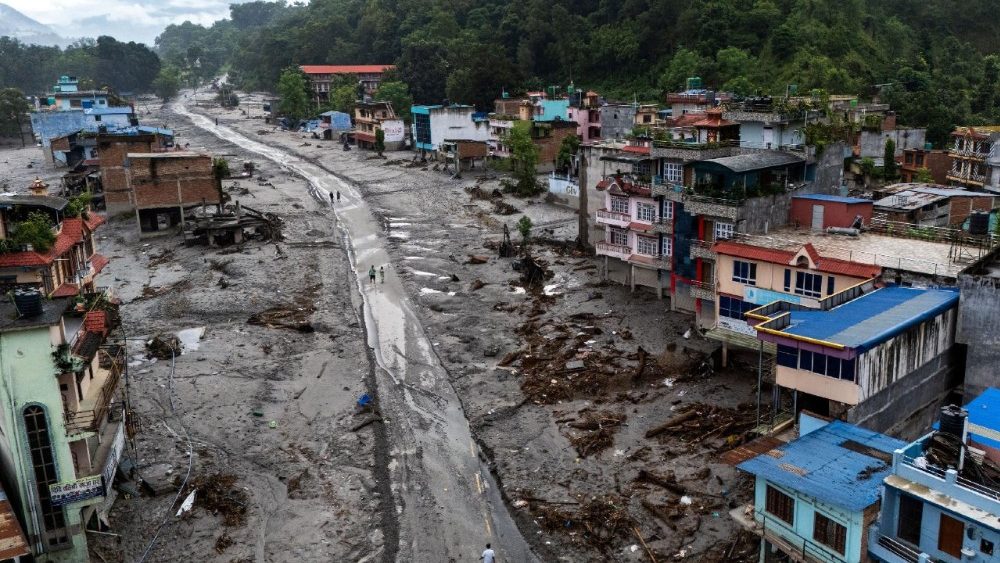 Imagens de drone mostram pessoas caminhando em uma estrada coberta de lama ao lado de casas danificadas após enchentes repentinas e deslizamentos de terra mortais em Devighat, distrito de Nuwakot, Nepal, em 30 de agosto de 2026. REUTERS/Athit Perawongmetha