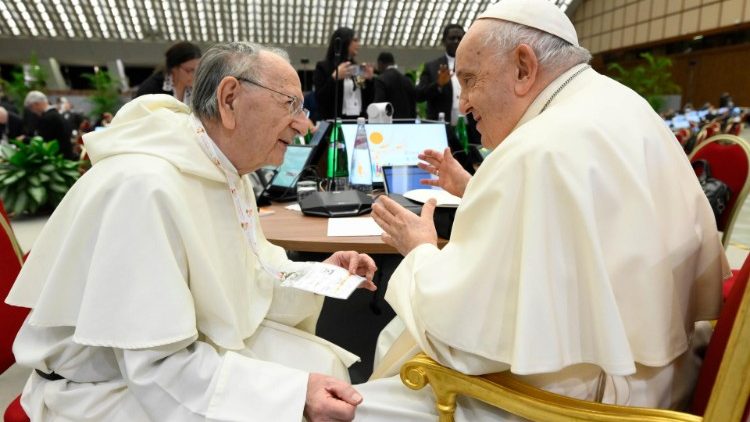 Papa Francisko akiwa na mmoja wa watawa wanaudhuria sinodi wakizungumza