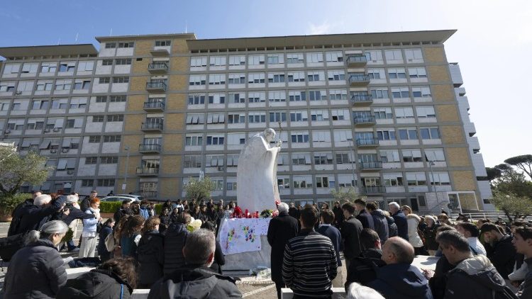 A group prays outside Rome's Gemelli hospital, where Pope Francis is currently undergoing treatment