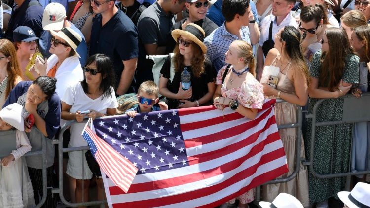 La bandera de Estados Unidos flamea entre la multitud que saluda al Romano Pontífice.