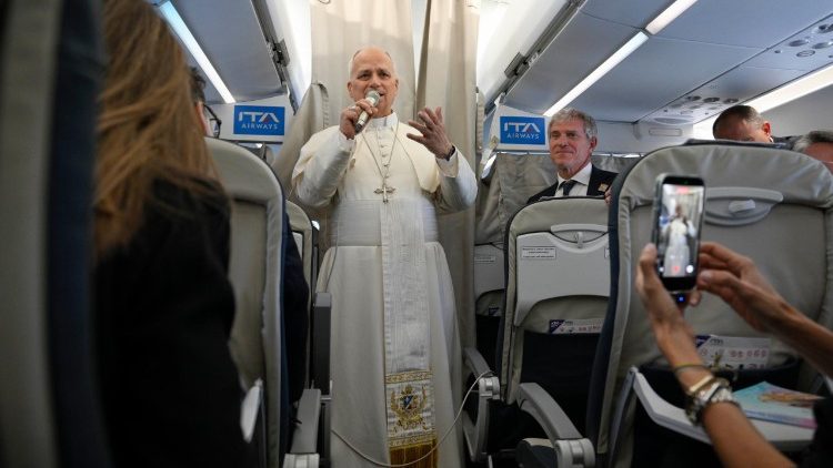 Pope Leo XIV greets journalists aboard the papal plane
