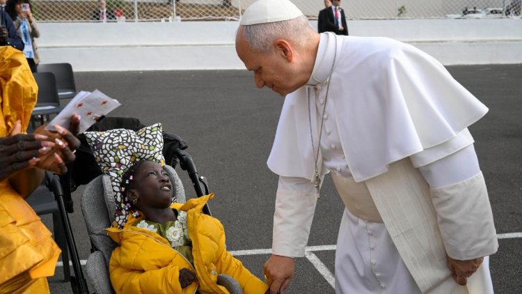 Leone XIV saluta una bambina al suo arrivo al centro Las Ra&iacute;ces. 
