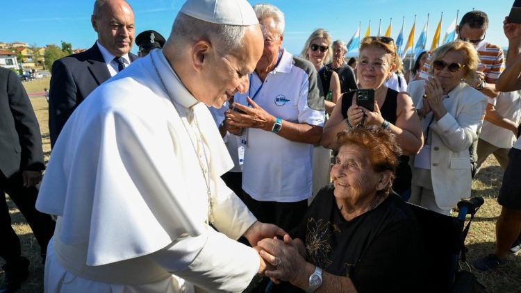  El Papa estrecha la mano de una mujer en silla de ruedas. 