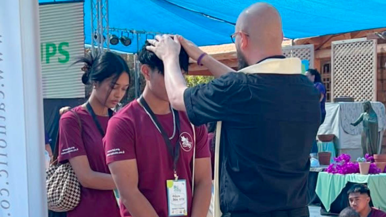 A priest offers a personal blessing during the Youth Festival.