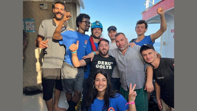 Migrants pose for a photo with volunteers from Mediterranea