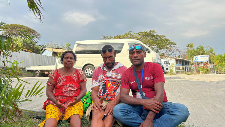 Da esquerda para a direita: Anna Dinz, Christopher Kenneth e John Junior Dinz, sentados do lado de fora da Igreja Católica de São João Apóstolo, depois de fazer uma viagem de dois dias de Mount Hagen a Port Moresby para a Viagem Apostólica do Papa Francisco