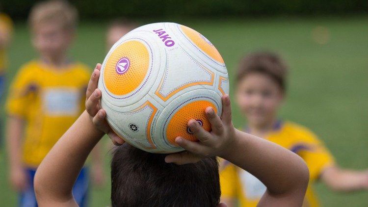 Crianças se divertem brincando com uma bola de futebol