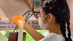 A student at Assumption Antipolo shields the candle with her hand during Eucharistic celebration marking Assumption Day, August 15, 2025. (Photo by Peter Monthienvichienchai / LiCAS News)