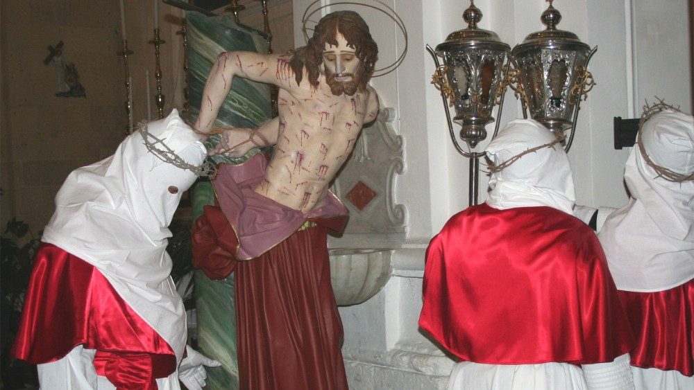 Montescaglioso, Processione dei Misteri, membri di una confraternita accanto al Cristo legato alla colonna