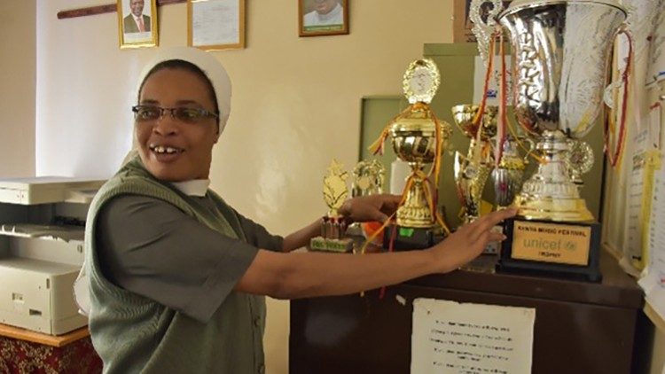 Schulleiterin Sr. Rose M. Gatimu zeigt Auszeichnungen für die außerschulischen Aktivitäten der Kinder