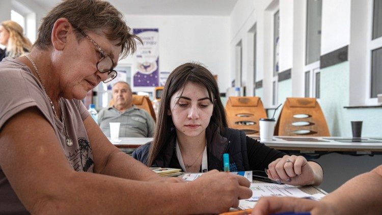 Lidia Hnatiuk helps recent evacuees from eastern Ukraine to fill out forms at Caritas Ternopil. (photo: Konstantin Chernichkin)