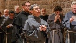 Fray Carlos Alberto Trovarelli (en el centro) en la cripta de la Basílica Inferior de Asís, reza ante la tumba de san Francisco