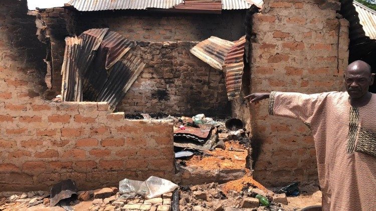 Un survivant montrant une maison détruite par les flammes.