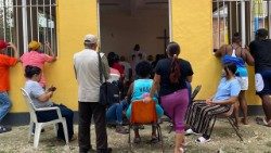 Migrantes em um centro de acolhimento enquanto participam da Santa Missa