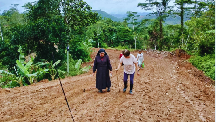 Sr. Erlinda auf schlammigen Dorfpfaden, um Familien der Gemeinde zu besuchen