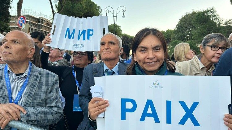 Marilu Grados h&auml;lt am Kolosseum  ein Schild mit der Aufschrift „Paix" (franz&ouml;sisch f&uuml;r Frieden)