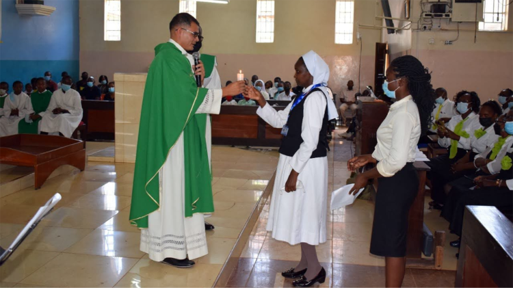 सिस्टर जुलियाना, नैरोबी महाधर्मप्रांत में संकेत भाषा अनुवादक के तौर पर अपनी काम की शुरुआत में फादर साल्वाडोर गोम्स एमजी से एक मोमबत्ती लेते हुए, जो पहले बधिरों के चैपलिन थे।