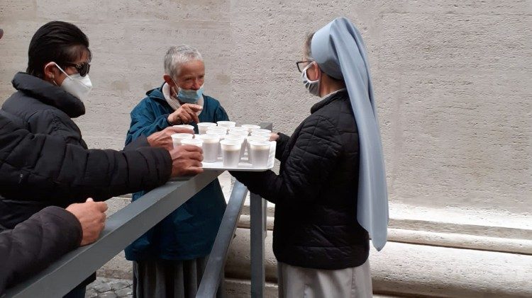 La distribuzione di bevande alle persone bisognose in attesa di fare la doccia sotto il Colonnato di San Pietro