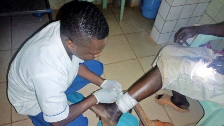 Un operatore del Saint Monica Catholic Health Center di Baba 1 presta cure a un anziano medicandogli una ferita. Foto: suor Shallotte Kum
